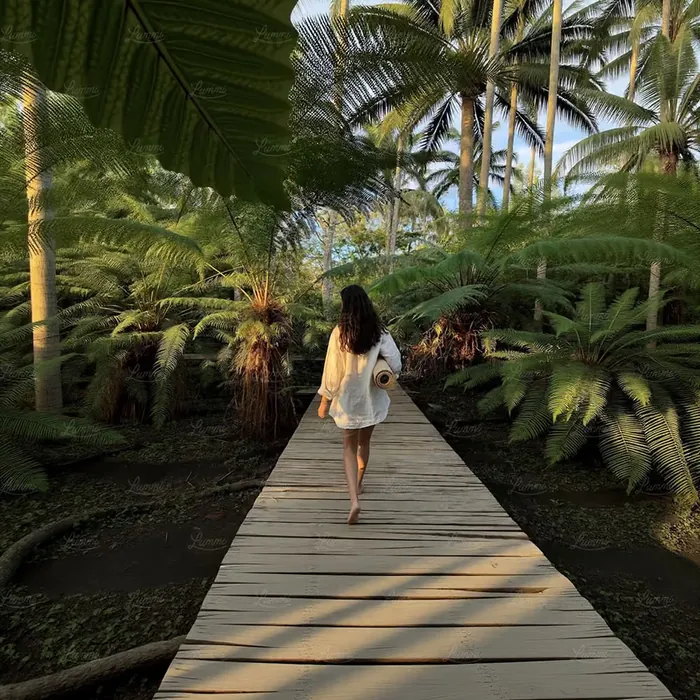 A woman walking barefoot along a wooden path through green ferns